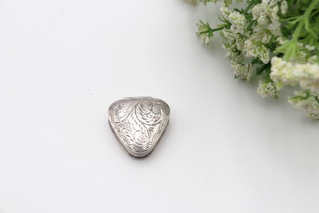 Caixa de comprimidos em prata triangular com gravados na tampa basculante